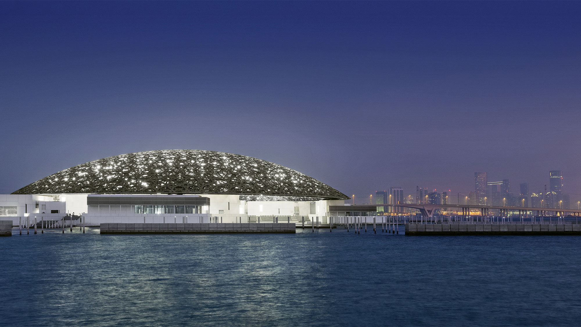 The Louvre Abu Dhabi with the Abu Dhabi skyline in the background.
