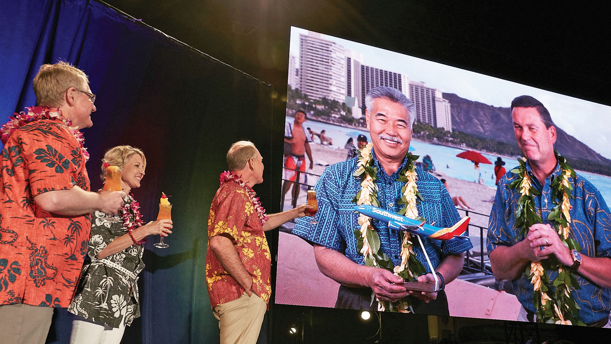 From left, Southwest COO Mike Van de Ven, managing director for culture Cheryl Hughey and CEO Gary Kelly toast the airline's news that it plans to serve Hawaii. Gov. David Ige and Southwest president Tom Nealon joined via satellite from Waikiki Beach.