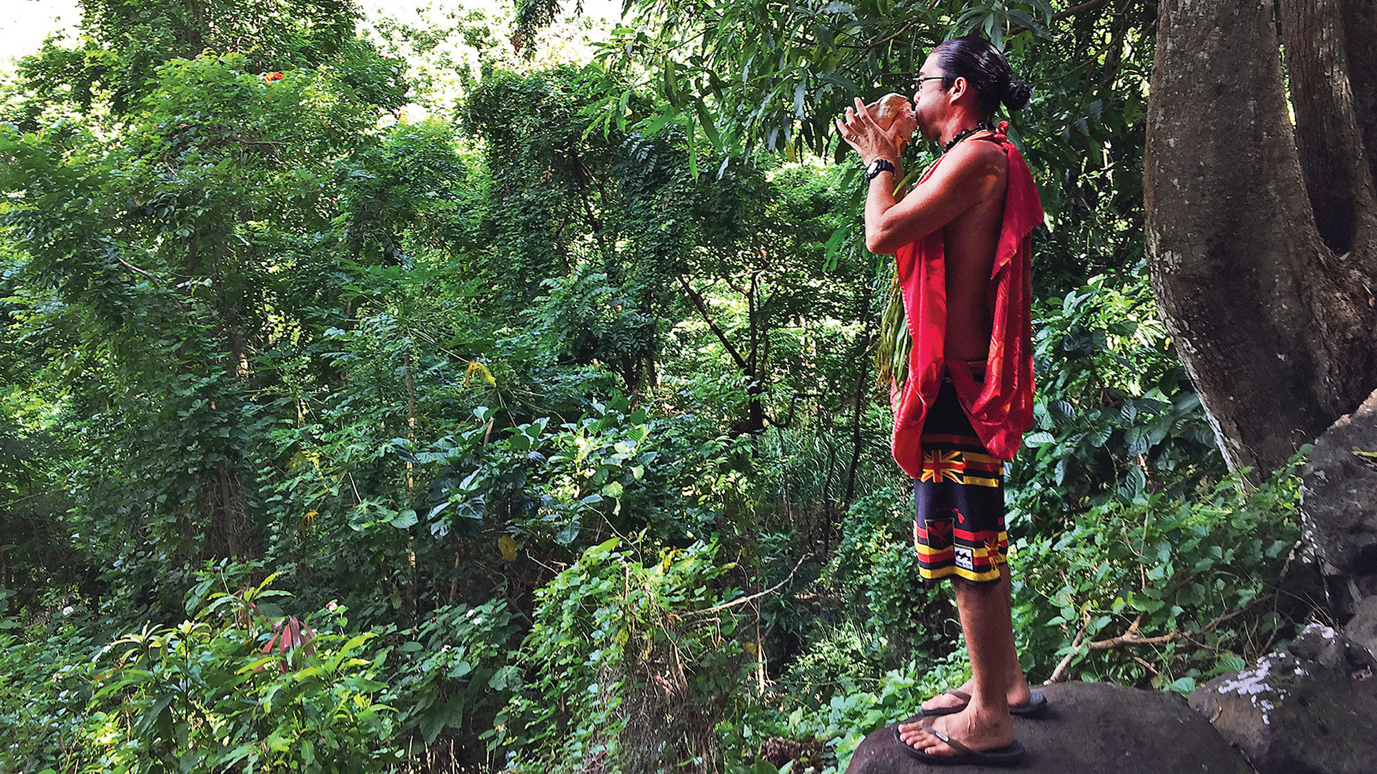 Greg Solatorio blows a conch to announce the arrival of visitors to his family’s land in the Halawa Valley on Molokai.