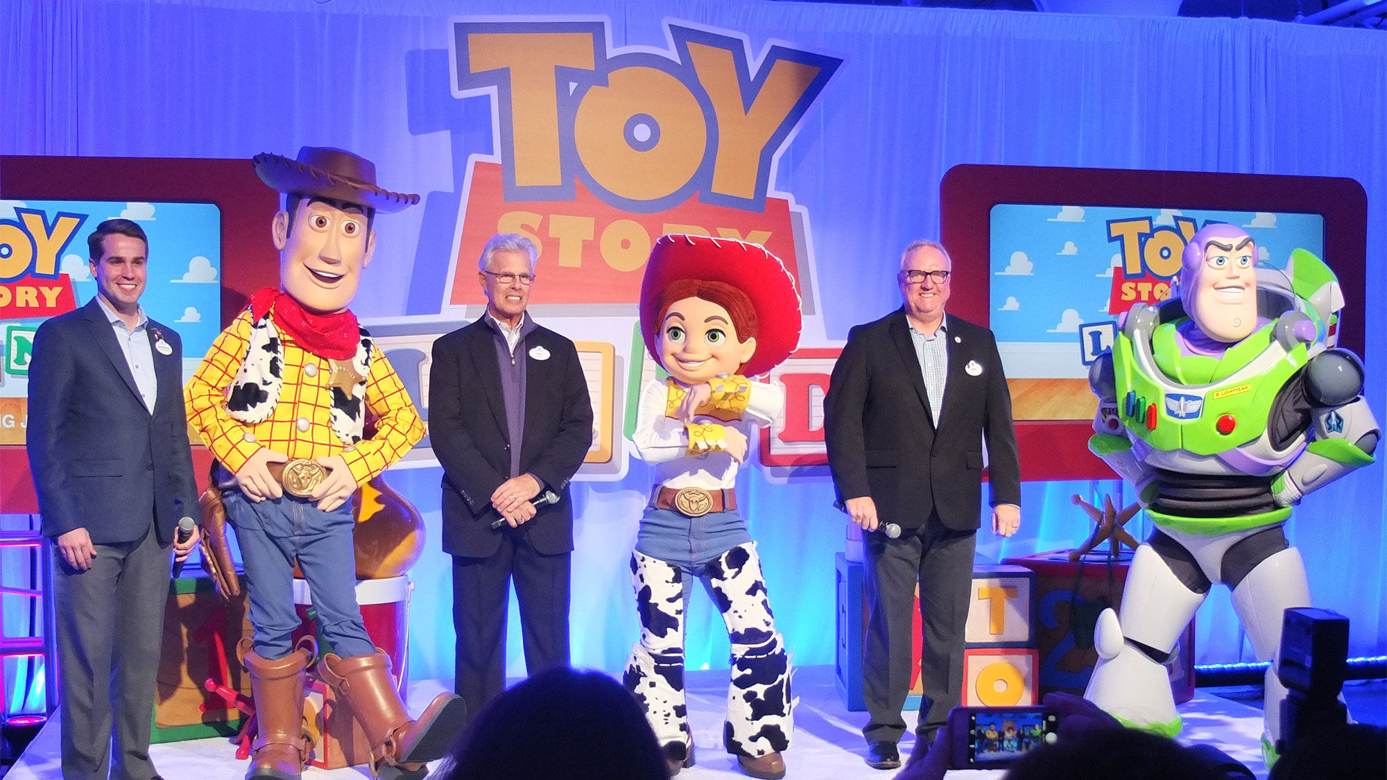 From left, Disney's Brandon Peters, Phil Holmes and Dave Minichiello were joined on stage by Toy Story characters Woody, Jessie and Buzz Lightyear.