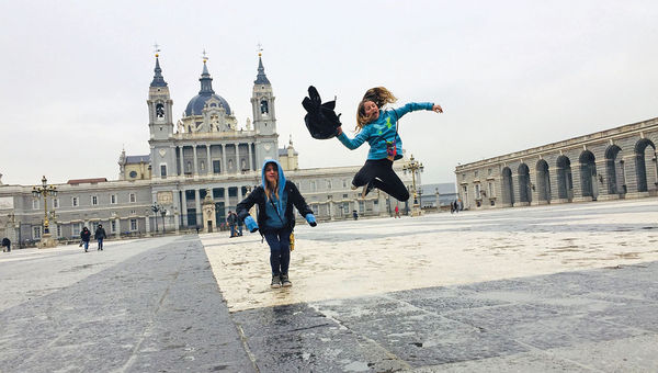 Twins jump for joy at Madrid’s massive Royal Palace, a highlight of their whirlwind trip to the city.