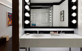 The star of the terrazzo-tiled bathroom is a custom Hollywood vanity with bubble lights inspired by Philip Johnson's iconic ladies lounge in New York City's former Four Seasons restaurant.