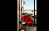 An authentic Eero Saarinen-designed Womb Chair, upholstered in red Knoll fabric, sits beside a Saarinen Pedestal tulip side table, where guests can make unlimited free international and local calls on a 1950s Western Electric 500 phone.