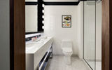 The glass-enclosed shower is subway-tiled in white with midnight-blue trim.