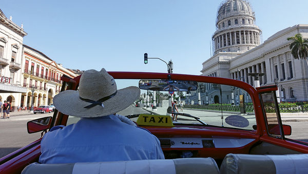 A classic-car tour of Havana passes El Capitolio.