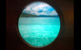 A virtual porthole on the wall shows a video loop of tropical waters.