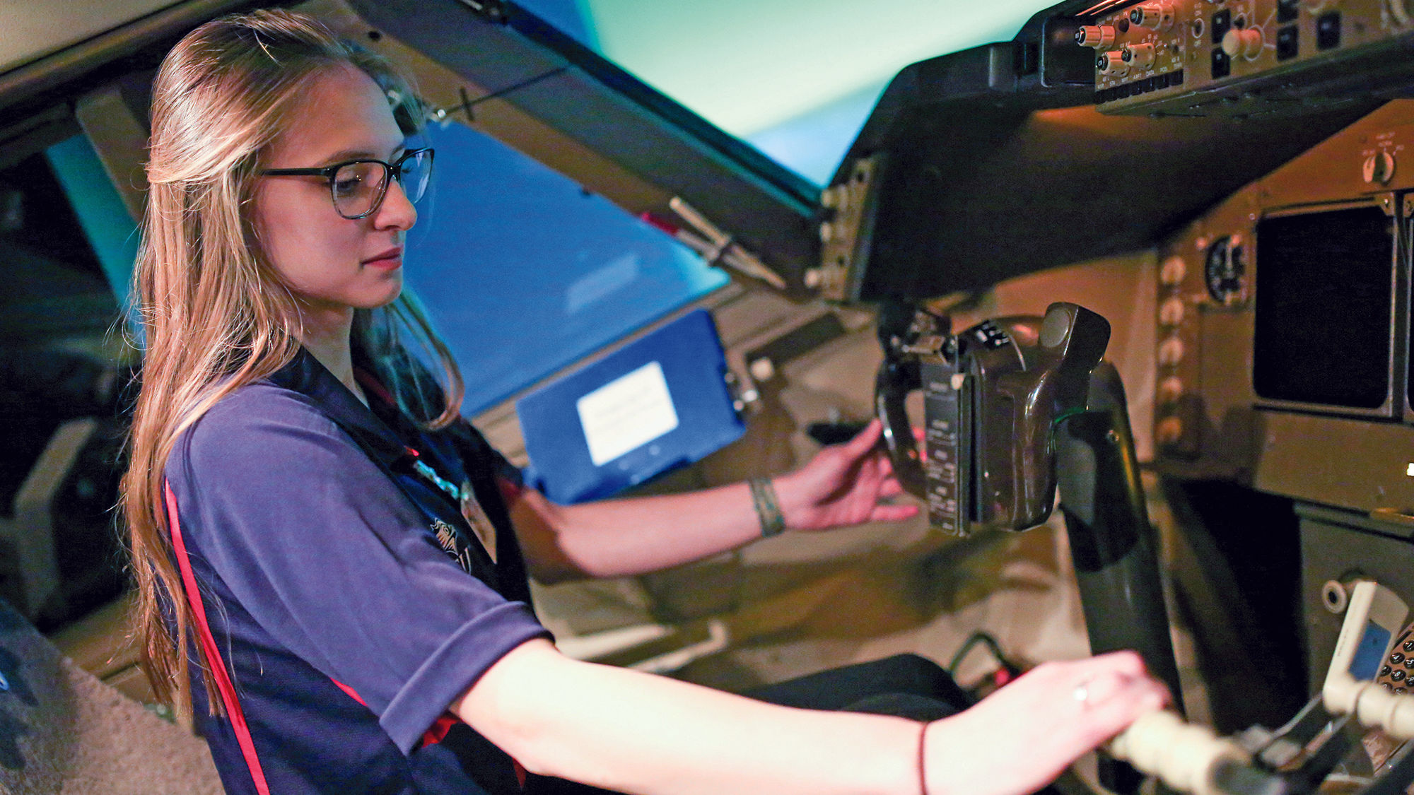 Madison Wolf, a senior aviation student at Metropolitan State University of Denver, operates a flight simulator at the United Airlines Flight Training Center.