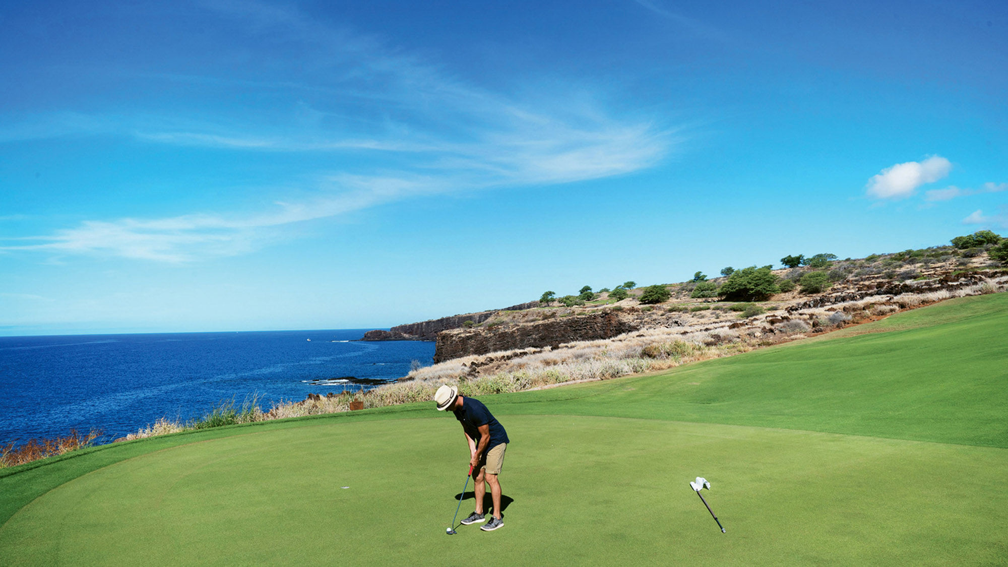 With a stunning ocean vista in the background, a golfer lines up a putt on one of Hawaii’s roughly 100 courses.
