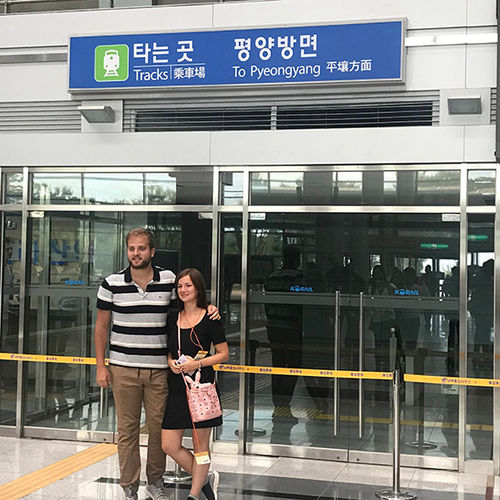 Tourists pose in front of a departure gate for Pyeongyang, North Korea. Tourists pose in front of a departure gate for Pyeongyang, North Korea.