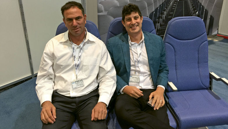 Travel Weekly's Robert Silk (left) and Seth Miller of PaxEx.Aero try out Molon Labe's staggered seats.