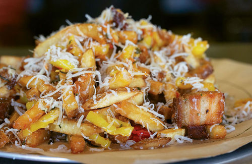 A plate of dirty fries — spuds buried in pork scraps, marinated peppers and Parmesan — at Lardo. A plate of dirty fries — spuds buried in pork scraps, marinated peppers and Parmesan — at Lardo.