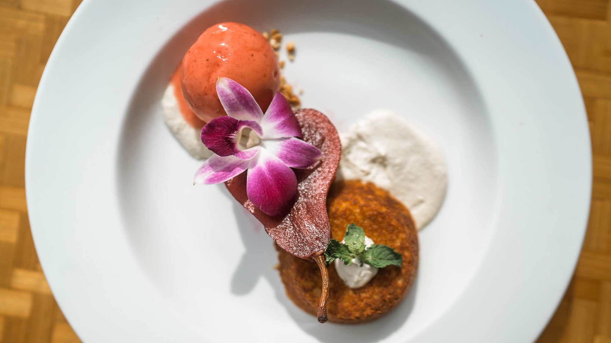 The Reef Bar and Market Grill now serves a vegan hibiscus-poached pear with almond cake and sweet cream, topped with a scoop of strawberry sorbet.