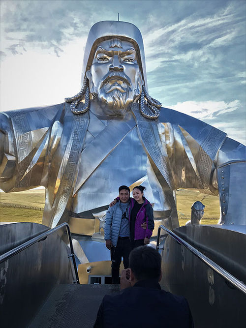 A couple poses for a photo at the top of the neck of Genghis Kahn's horse in a giant equestrian statue of the warlord.