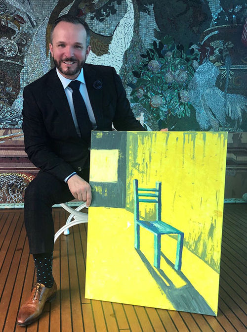 Uniworld senior vice president of global sales Kristian Anderson and the painting of a chair given to him at the company’s Kickoff event.
