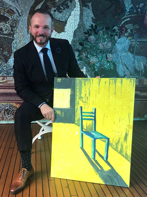 Uniworld senior vice president of global sales Kristian Anderson and the painting of a chair given to him at the company’s Kickoff event. Uniworld senior vice president of global sales Kristian Anderson and the painting of a chair given to him at the company’s Kickoff event.