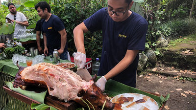 Meat from a roast suckling pig is being trimmed on a central Bali farm for lunch served to guests on a Silversea Cruises expedition.