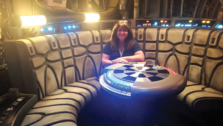 Mouse Fan Travel CEO Beci Mahnken sitting at the iconic Dejarik game table on the queue of Millennium Falcon: Smugglers Run.