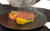 Main-course salmon steak served under a dome filled with apple wood smoke.