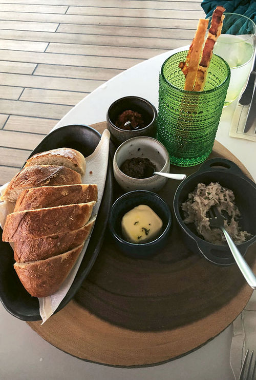 A meal at Earth and Ocean begins with bread and spreads delivered tableside on a trolley. A meal at Earth and Ocean begins with bread and spreads delivered tableside on a trolley.