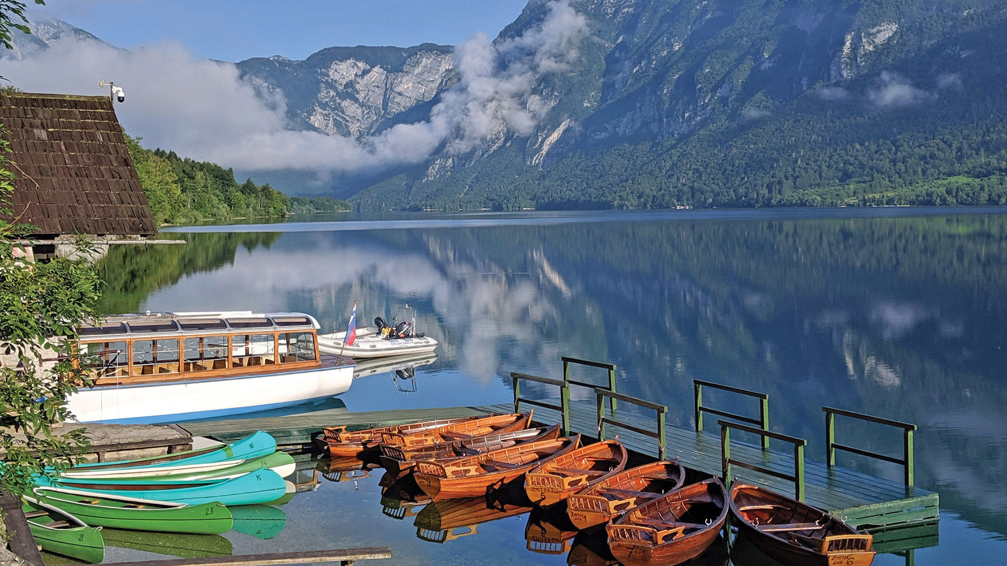 Rowboats and canoes on crystal-clear Lake Bohinj in Slovenia.