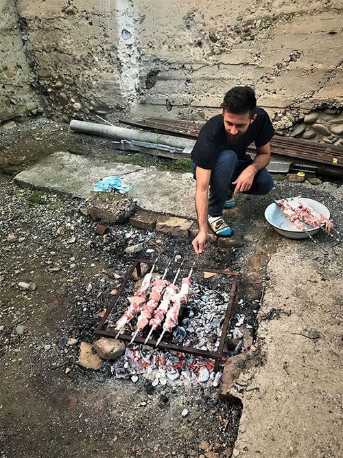 Tamaz Kenkebashvili (with the same name as his grandfather) tends to pork skewers over a charcoal pit. Tamaz Kenkebashvili (with the same name as his grandfather) tends to pork skewers over a charcoal pit.