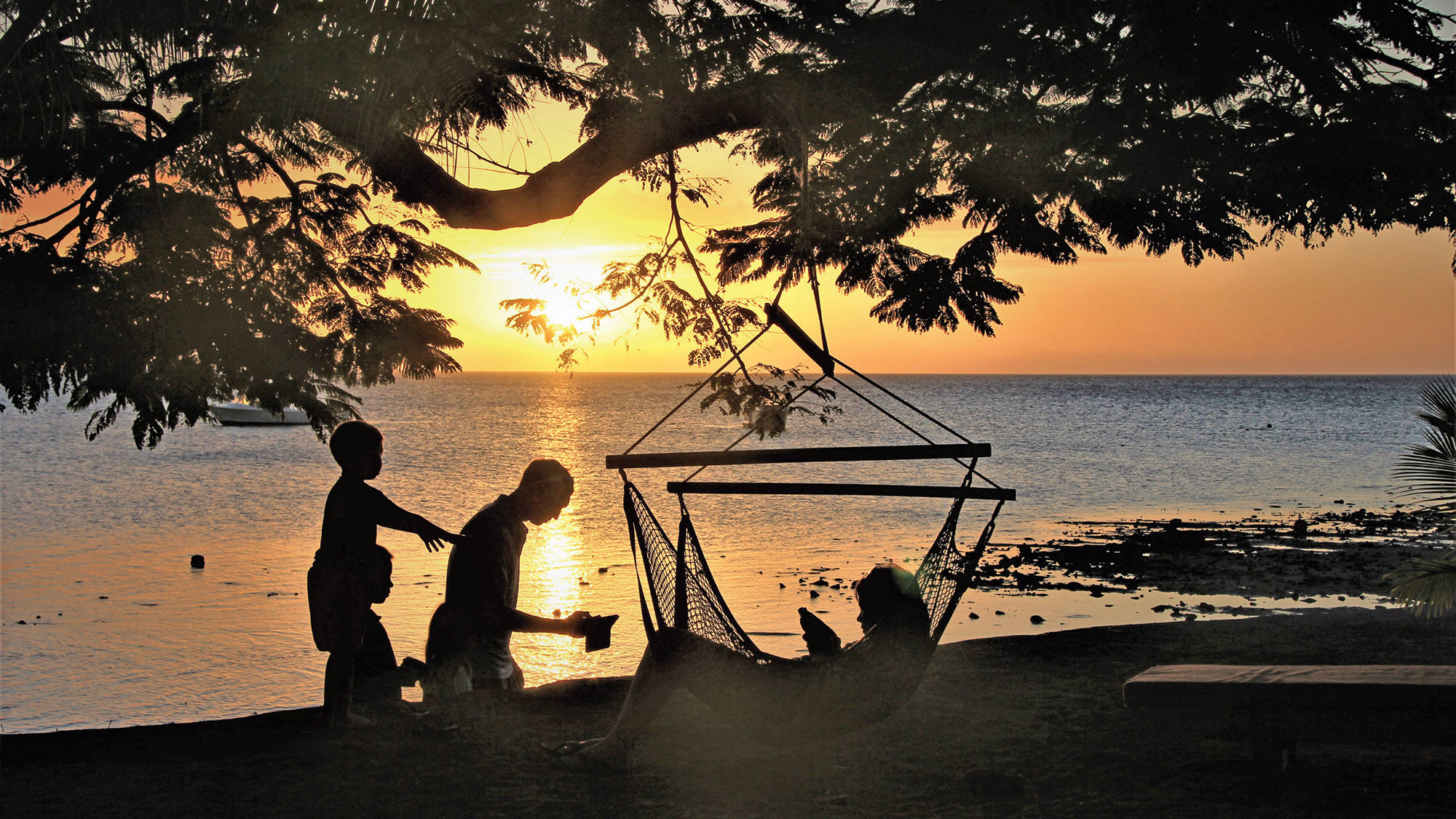 A family at dusk on the waterfront of the Volivoli Beach Resort.