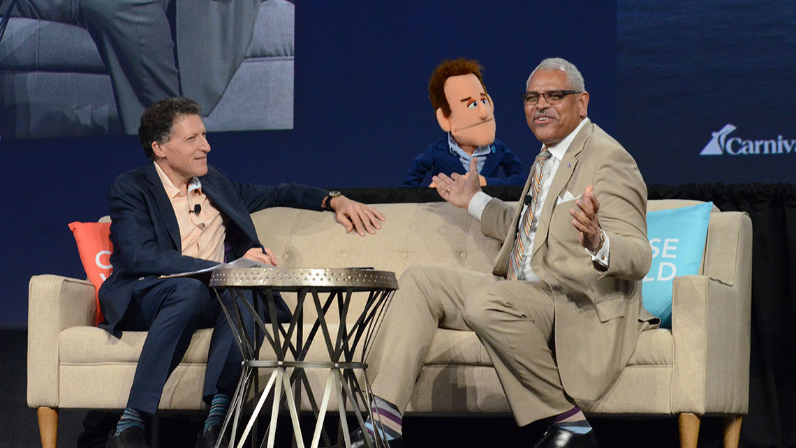 Carnival Corp. CEO Arnold Donald, far right, was joined onstage during the CEO Conversation panel by John Chernesky-the-puppet of Princess Cruises. The session was moderated by editor in chief Arnie Weissmann, seated, left.
