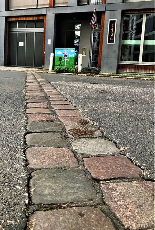 A line of cobblestones in a street indicate where the Berlin Wall stood, with the West German neighborhood Kreuzberg to the left and the East Berlin neighborhood Friedrichshain to the right. A line of cobblestones in a street indicate where the Berlin Wall stood, with the West German neighborhood Kreuzberg to the left and the East Berlin neighborhood Friedrichshain to the right.