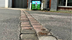 A line of cobblestones in a street indicate where the Berlin Wall stood, with the West German neighborhood Kreuzberg to the left and the East Berlin neighborhood Friedrichshain to the right.