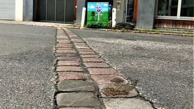 A line of cobblestones in a street indicate where the Berlin Wall stood, with the West German neighborhood Kreuzberg to the left and the East Berlin neighborhood Friedrichshain to the right.