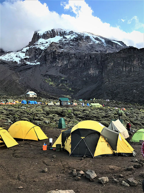 The escarpment known as Barranco Wall, beginning at the edge of this campsite, must be scaled to get to the peak of Kilimanjaro behind it. The escarpment known as Barranco Wall, beginning at the edge of this campsite, must be scaled to get to the peak of Kilimanjaro behind it.