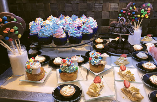 A dessert buffet meant to please the kids. Sweets are topped by blue frosting and meringue toadstools.