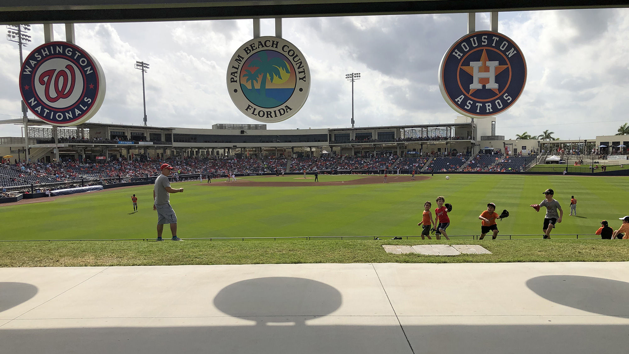 A Dad plays catch with kids on the outfield embankment of FitTeam Ballpark of the Palm Beaches in West Palm Beach during a spring training game in early March.