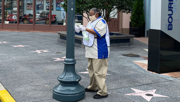 A Universal employee sanitizing a lamp post, a potentially high-touch area. A Universal employee sanitizing a lamp post, a potentially high-touch area.