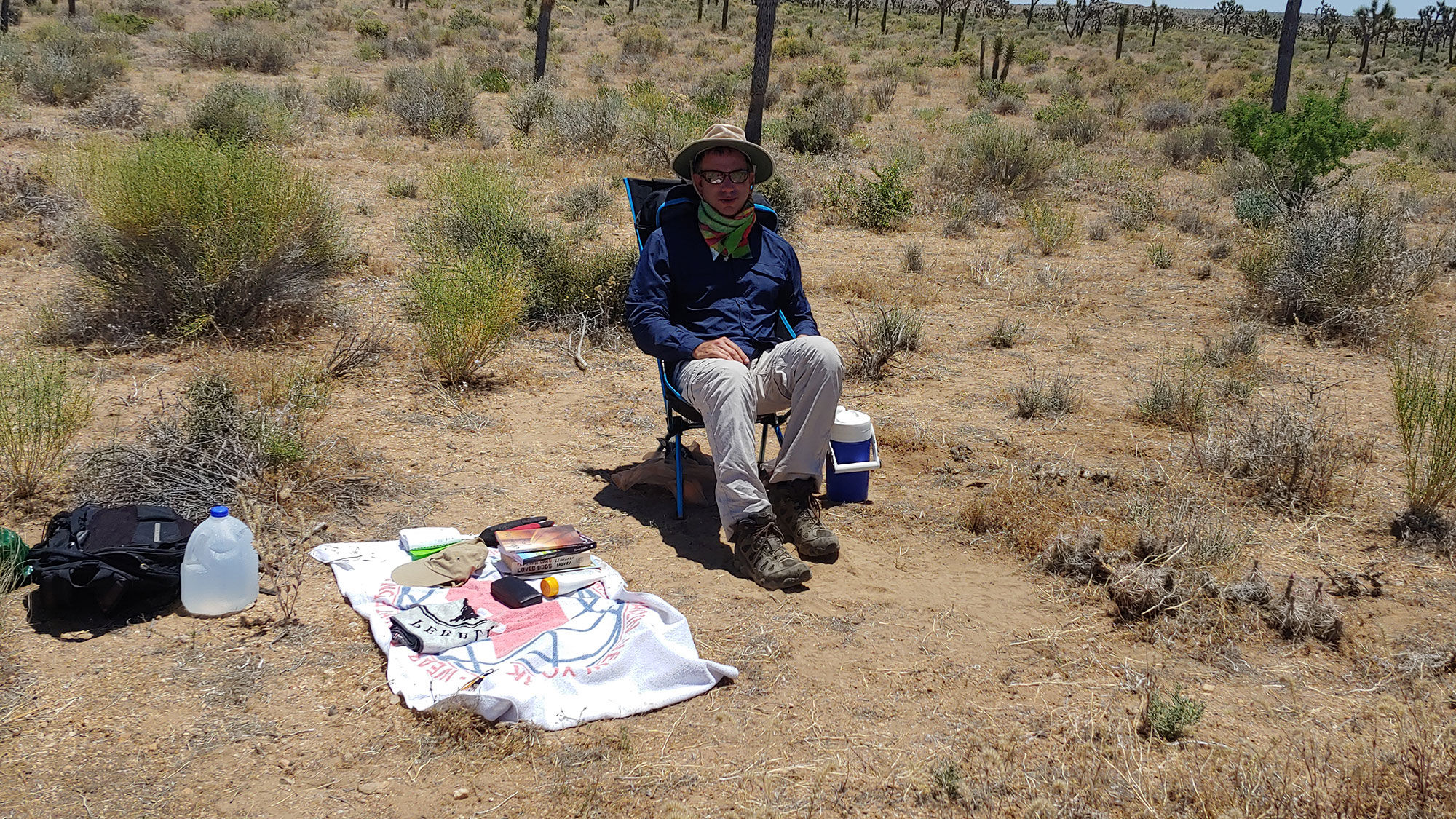 In situ: The author, fortified with provisions and sun protection, as his day of sitting in the Mojave Desert enters its final few hours.