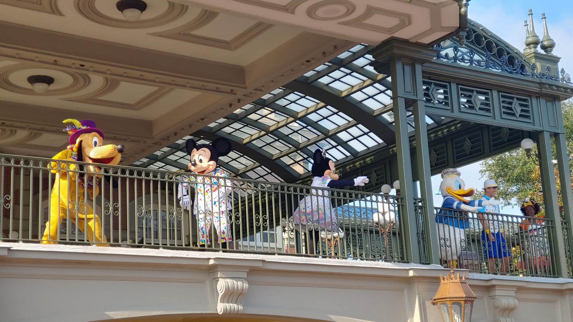 Disney characters still appear in the parks, albeit in a socially distant manner. Here, characters interact with guests from the second story of the Magic Kingdom's train station.