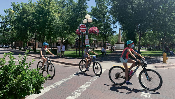 Cyclists circle a largely empty plaza in Santa Fe, which normally is bustling with tourists in the summer.
