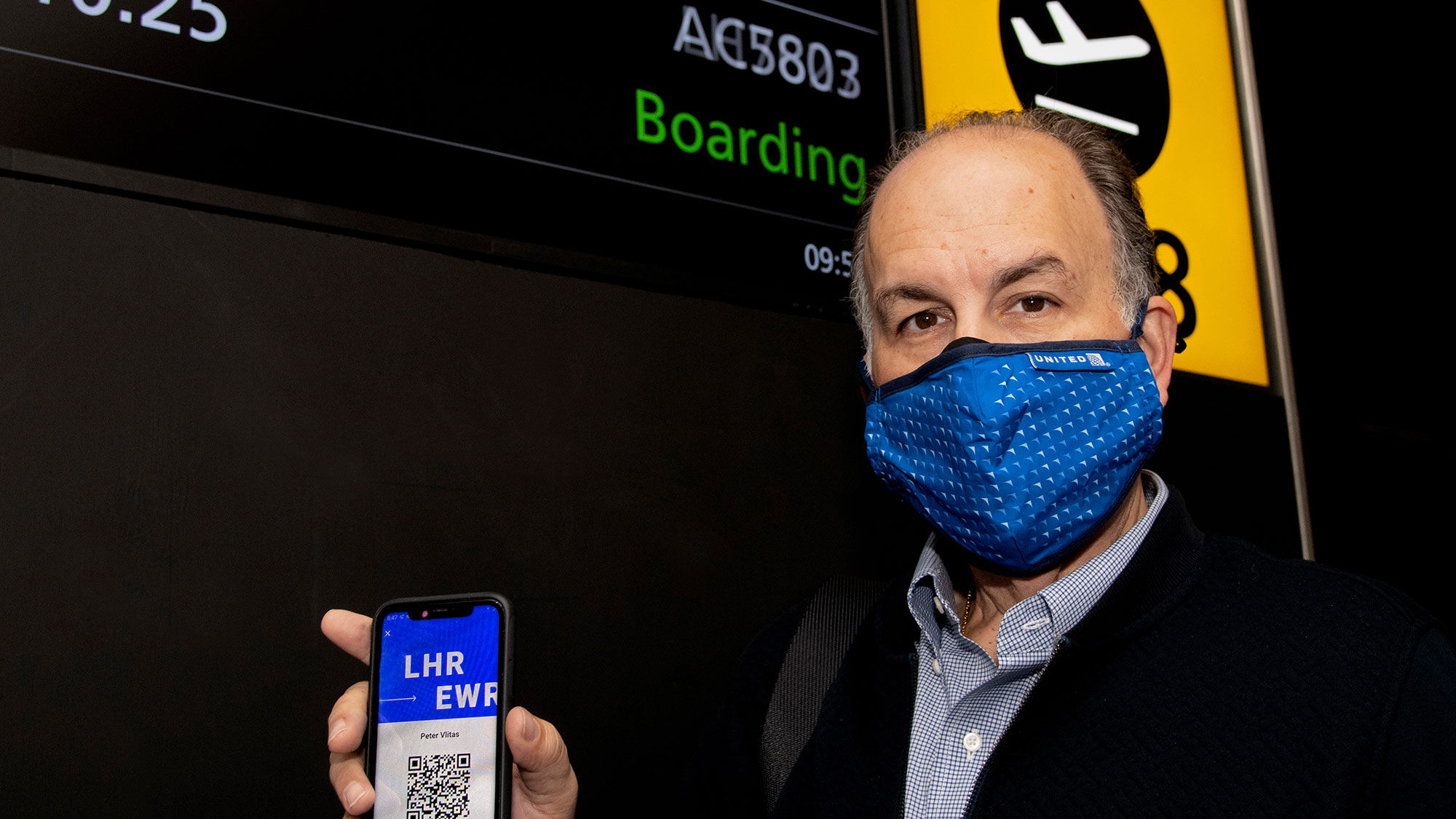 Internova's Peter Vlitas holds up his unique QR code on the CommonPass health pass before boarding his flight from London to Newark.