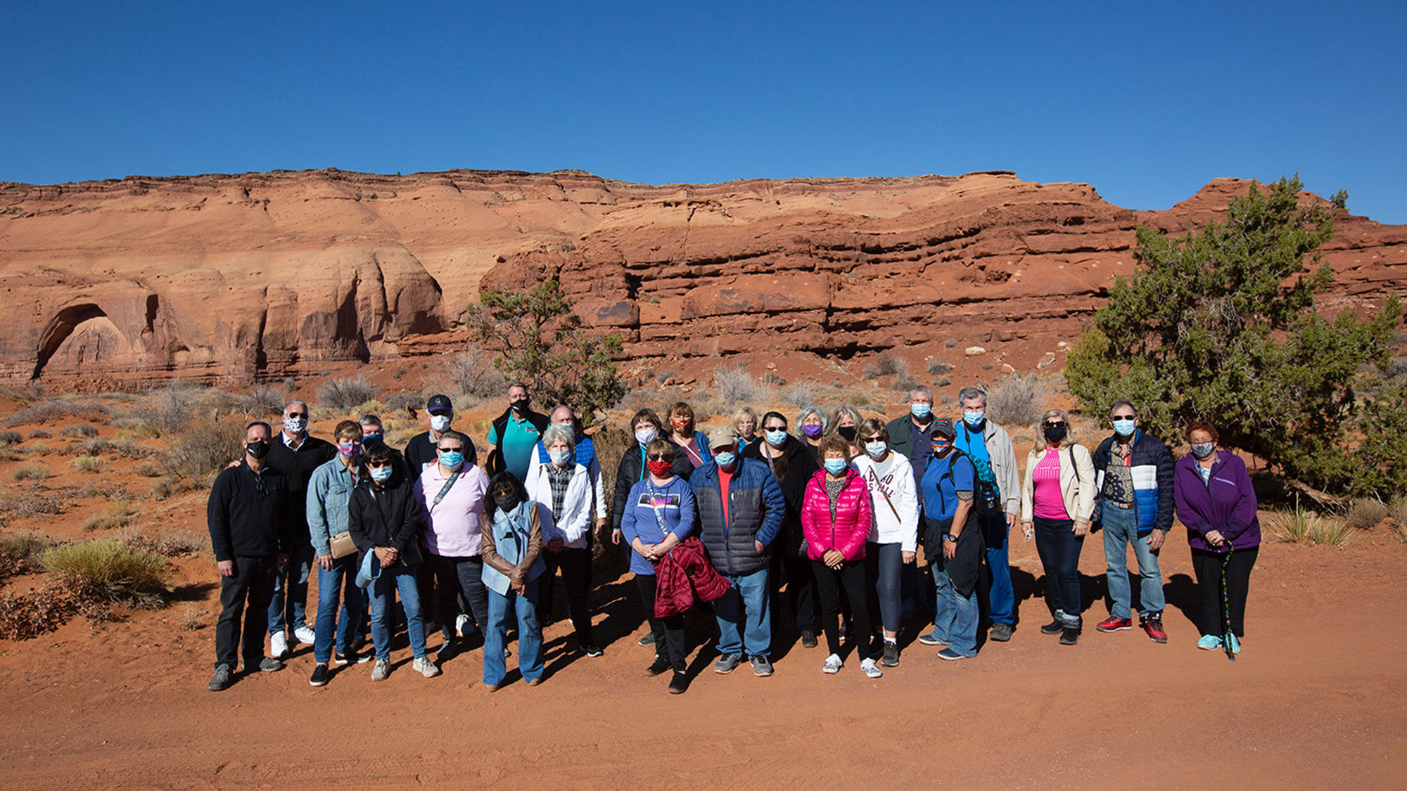 Guests wearing masks for a group photo on a Globus tour in Monument Valley, Ariz.