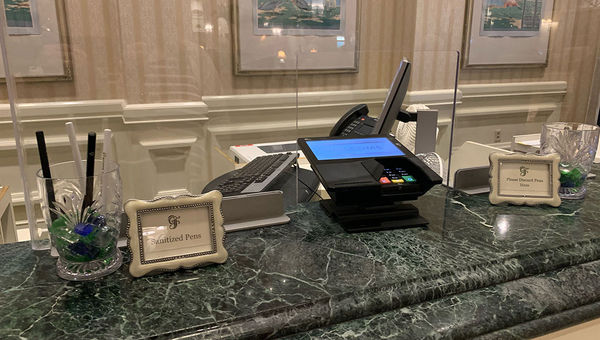 The check-in counters at the Grand Floridian resort at Walt Disney World have plexiglass shields and cups for sanitized and used pens. The check-in counters at the Grand Floridian resort at Walt Disney World have plexiglass shields and cups for sanitized and used pens.
