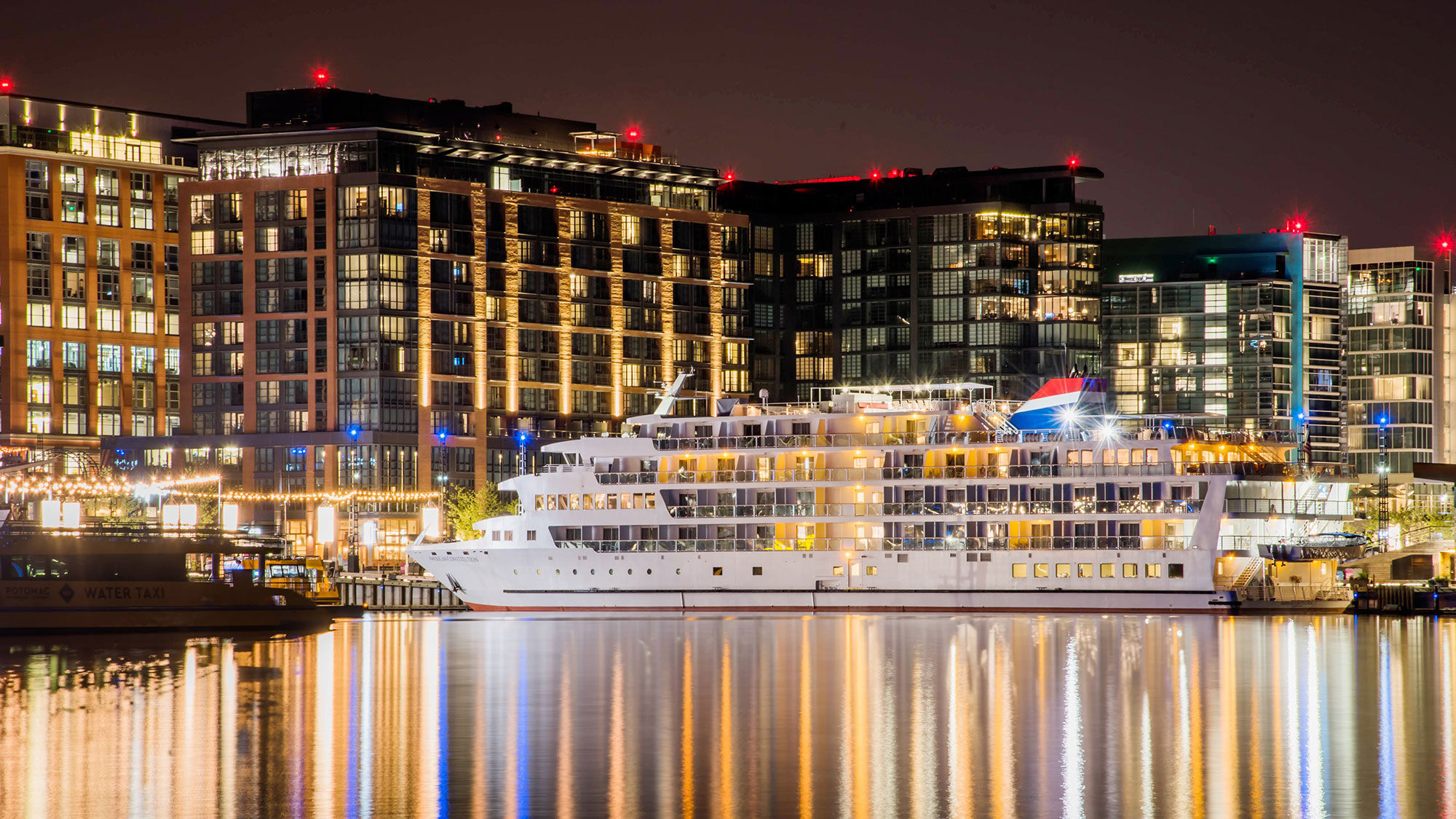 American Cruise Lines' American Constitution docked at the Wharf in Washington, D.C., at night.