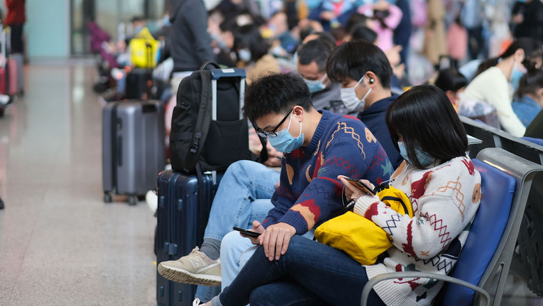 Travelers in face masks wait in the train station in Wuhan, China, earlier this month.