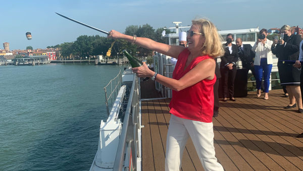 Uniworld Boutique River Cruises' CEO sabers the top of a champagne bottle to celebrate the renaming of the S.S. La Venezia.