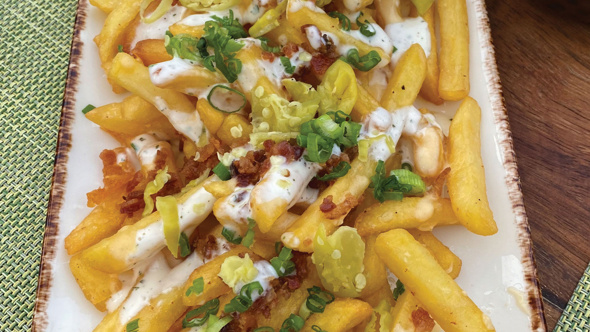 The Train Wreck Fries at the Rooftop Garden Grill on the Celebrity Edge, topped with bacon, scallions, four cheeses, hot peppers and ranch dressing.