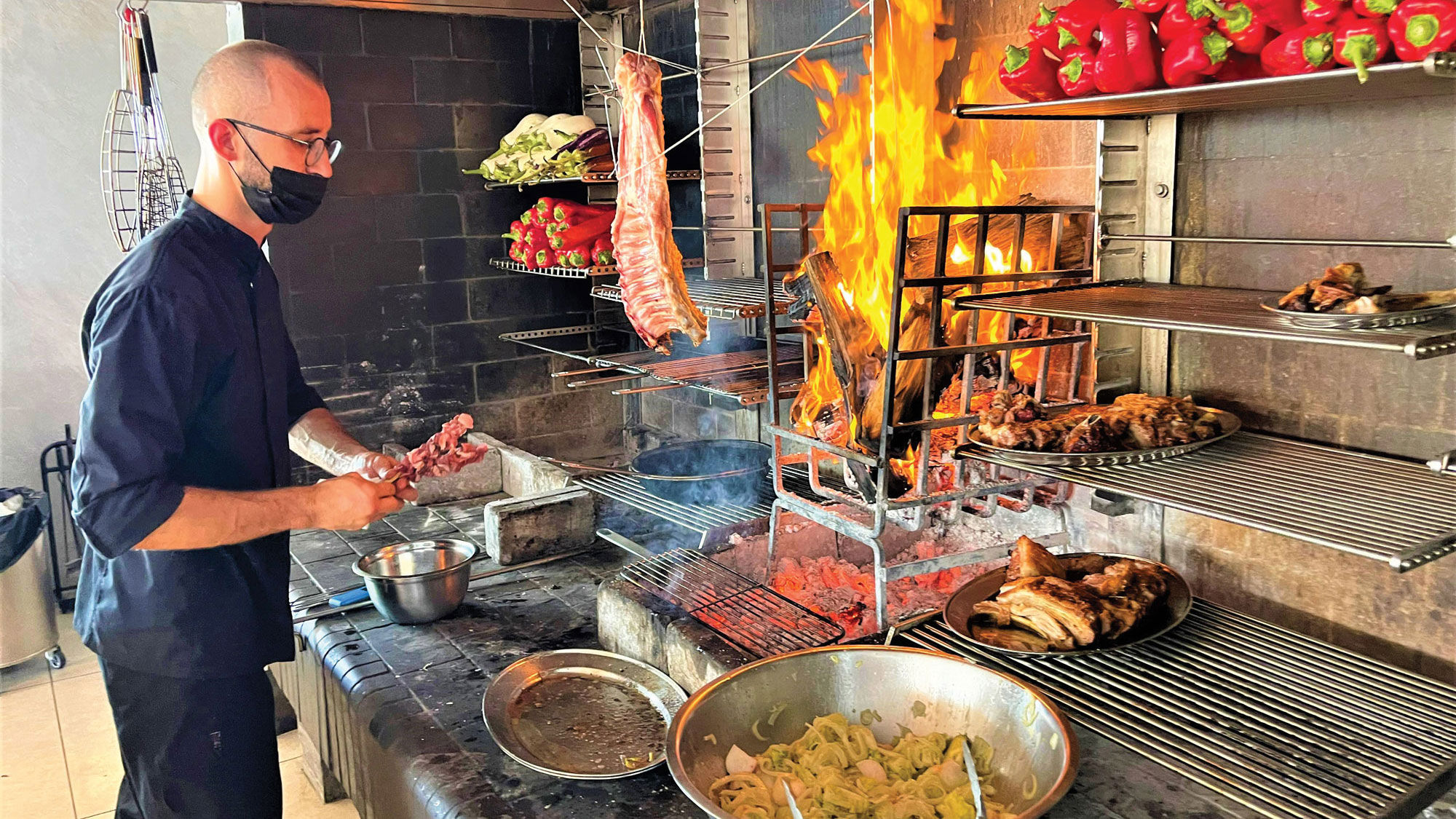 A cook at Vezene, a restaurant on Santorini, prepares food for guests on a SALT Ashore excursion.