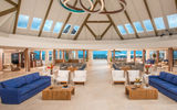 The airy lobby space and seating area with a direct view of turquoise waters and white sand beach greets today's guests arriving at Sandals Montego Bay.