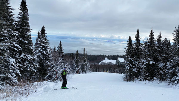A skier is backed by the St. Lawrence River at Massif Charlevoix. The resort sits at the base of the ski area.