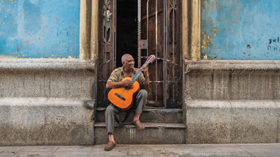 A musician plays a guitar in Cuba. Tour operators report rising interest in trips to the island nation.