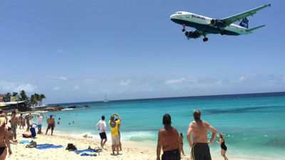 A JetBlue aircraft flies low over the beach on its approach to St. Maarten.
