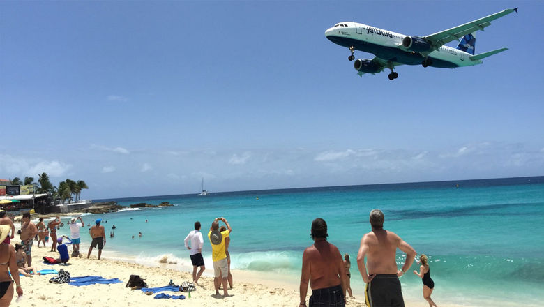 A JetBlue aircraft flies low over the beach on its approach to St. Maarten.